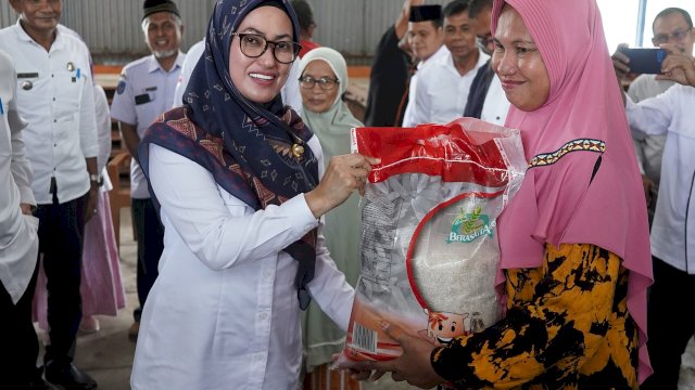 Bupati Luwu Utara Indah Putri Indriani menyerahkan bantuan beras kepada salah satu masyarakat masyarakat di Keca,atan Tanalili. (ist)