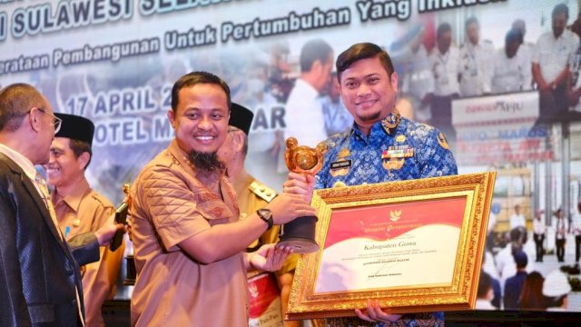 Bupati Gowa Adnan Purichta Ichsan saat menerima penghargaan Kategori Kabupaten dengan Komitmen Tinggi dalam Perencanaan Pembangunan Daerah yang Responsif Gender, Anak dan Disabilitas oleh Gubernur Sulawesi Selatan Andi Sudirman Sulaiman, disela-sela Musrenbang RKPD Provinsi Sulawesi Selatan Tahun 2024, di Phinisi Ballroom, Hotel Claro Makassar, kemarin. (Dok. Humas Gowa)