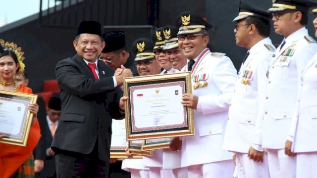 Menteri Dalam Negeri Tito Karnavian menyerahkan penghargaan status kinerja terbaik tertinggi secara nasional untuk Kota Makassar dalam Upacara Peringatan Hari Otonomi Daerah Ke-27, di Anjungan City Of Makassar, Sabtu (29/4/2023). (Foto: Istimewa)