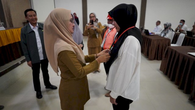 Bupati Luwu Utara Indah Putri Indriani saat menyematkan kartu tanda peserta Bimtek Sistem Manajemen Keselamatan Kontruksi (SMKK) kepada salah satu peserta. Selasa (18/07/2023)