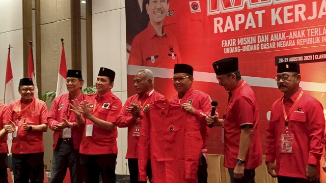 Ketua Badan Kehormatan DPP PDIP, Komarudin Watubun memakaikan jaket dan menyerahkan KTA ke Wali Kota Makassar, Moh Ramdhan Pomanto dalam Rakerda III PDIP Sulsel di Hotel Claro, Makassar, Senin (28/8/2023). (Foto: Istimewa)