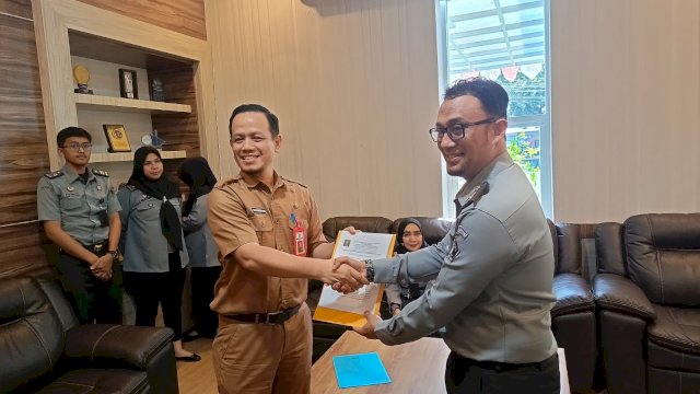 Kadivyankum Kanwil Kemenkumham Sulsel Hernadi saat menyerahkan berkas produk hukum daerah yang telah di harmonisasi. (Dok. Humas Kanwil Kemenkumham Sulsel)