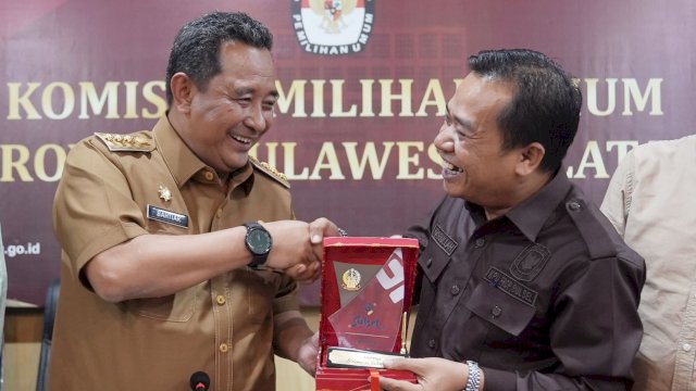 Pj Gubernur Sulsel Bahtiar Baharuddin, menyerahkan cendera mata kepada Ketua KPU Sulsel Hasbullah, Senin (11/09/2023). (Istimewa)