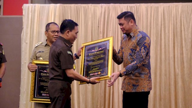 Bupati Gowa Adnan Purichta Ichsan saat menerima penghargaan dari Kepala Kejaksaan Tinggi Sulawesi Selatan sebagai role model kepala daerah yang diserahkan Plh. Kajati Sulsel Leonard Eben Ezer Simanjuntak, di Sandeq Ballroom, Hotel Claro Makassar, Jum'at (22/03/2024). (Dok. Humas Gowa)