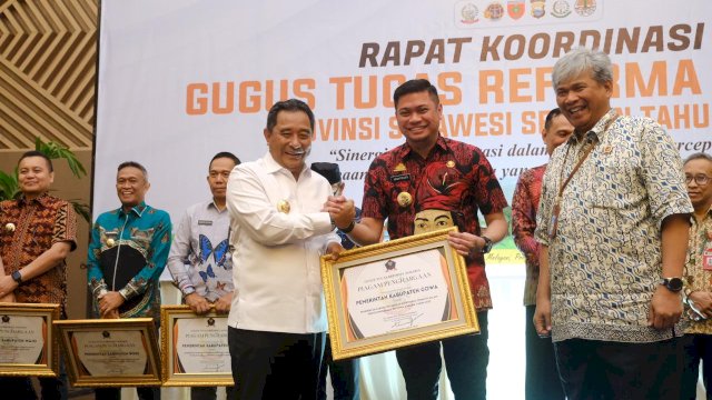 Pj Gubernur Sulsel Bahtiar Baharuddin saat menyerahkan penghargaan kepada Bupati Gowa, Adnan Purichta Ichsan dengan kategori Pemerintah Kabupaten dengan Kontribusi Teraktif dalam Penyelenggaraan Reforma Agraria Tahun 2023, di Claro Hotel Makassar, kemarin. (Dok. Humas Gowa)