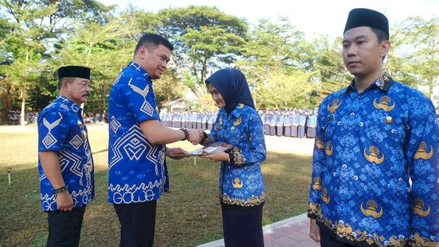 Bupati Gowa, Adnan Purichta Ichsan bersama Wakilnya Abd Rauf Malaganni saat menyerahkan SK kepada salah satu tenaga PPPK pada Apel Serah Terima Surat Keputusan Pengangkatan PPPK Formasi Tahun 2023 Lingkup Pemerintah Kabupaten Gowa, di Lapangan Upacara Kantor Bupati Gowa, Jumat, (31/05/2024). (Dok. Humas Gowa)