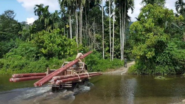 Petugas PLN membawa material pendukung kelistrikan menembus sungai ke Desa Gunung Menasaha, Kabupaten Aceh Jaya, yang jaraknya kurang lebih 200 kilometer dari Banda Aceh. (Istimewa)