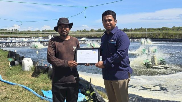 Penyerahan Renewable Energy Certificate oleh Team Leader Pelayanan Pelanggan PLN Unit Layanan Pelanggan Takalar, Andy Mulya (kanan) kepada pemilik tambak udang vaname di Kabupaten Takalar, Sardi (kiri).