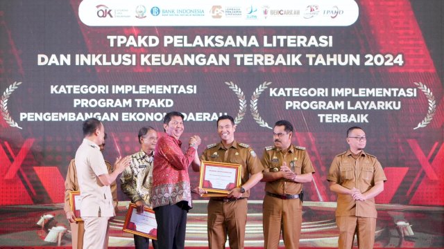 Kepala OJK Sulselbar Darwisman (batik merah) saat memberikan penghargaan kepada salah satu TPAKD terbaik, di sela-sela Pembukaan TPAKD Summit 2024, di Ruang Pola Kantor Gubernur Sulawesi Selatan, kemarin. (Dok. Humas OJK)