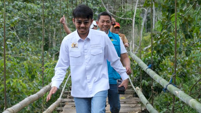 Anggota DPR RI Komisi VI, Ismail Bachtiar dan GM PLN UID Sulselrabar, Edyansyah saat melewati jembatan setapak untuk meresmikan nyala listrik di Kampung Menra, Kabupaten Sinjai, Senin (2/6/2025). (Foto: Istimewa)