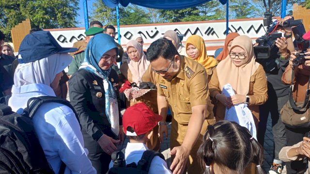 Bupati Gowa, Sitti Husniah Talenrang dan Wakilnya Darmawangsyah Muin (Hati Damai) saat memasangkan seragam sekolah gratis secara simbolik, di sela-sela Apel Besar Launching Program Seragam Gratis Siswa-Siswi Jenjang SD-SMP se-Kabupaten Gowa, di Lapangan Sultan Hasanuddin, Senin, (07/06/2025). (Dok. Chaerani/Republiknews.co.id) 