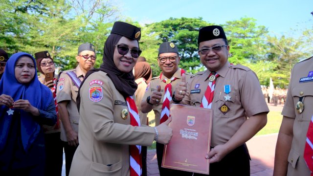 Bupati Gowa yang juga Ketua Kwarcab Pramuka Kabupaten Gowa, Sitti Husniah Talenrang saat memberikan tanda penghargaan ke Wabup Gowa yang juga Waka Kwarcab Pramuka Kabupaten Gowa Darmawangsyah Muin, di sela-sela Upacara Peringatan Hari Ulang Tahun (HUT) Ke-64 Gerakan Pramuka, di Lapangan Upacara Kantor Bupati Gowa, Rabu, (13/08/2025). (Dok. Humas Gowa) 