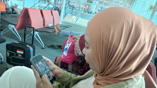 Sutriani saat mengenakan ponsel pintarnya untuk membuat konten video di ruang tunggu Bandara Sultan Hasanuddin, belum lama ini. Sebagai seorang konten kreator kualitas jaringan menjadi kebutuhan penting. (Dok. Chaerani/Republiknews.co.id)