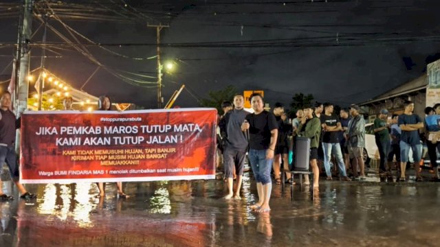 Warga Perumahan Bumi Findaria Mas 1 di Kecamatan Moncong Loe, Kabupaten Maros, menggelar aksi protes di tengah genangan banjir pada Kamis (13/11/2025) malam. (Foto: Istimewa)