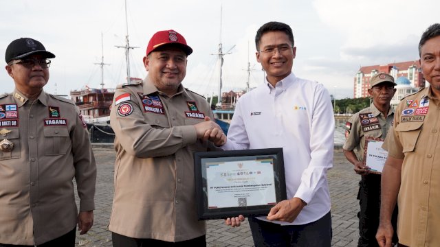 Wali Kota Makassar, Munafri Arifuddin saat menyerahkan penghargaan kepada General Manager PLN UIP Sulawesi, I Gusti Made Aditya San Adinatha, pada Apel Pengukuhan dan Simulasi Uji SOP Kampung Siaga Bencana, di Anjungan MNEK, Kawasan CPI Makassar, kemarin. (Dok. Humas PLN UIP Sulawesi) 