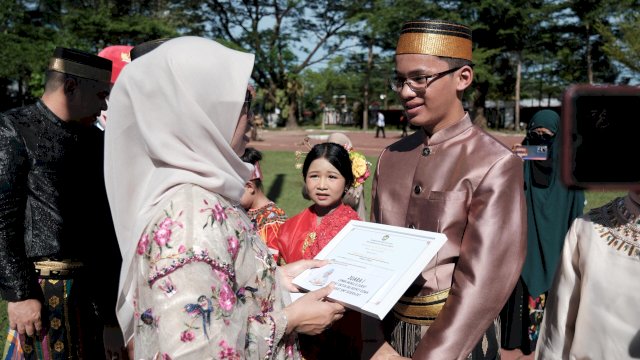 Bupati Gowa, Sitti Husniah Talenrang saat memberikan hadiah kepada salah satu pemenang Lomba Menulis Surat untuk Bupati Gowa, Muhammad Afatih Amir, di sela-sela Peringatan Hardiknas Tingkat Kabupaten Gowa Tahun 2026, di Lapangan Upacara Kantor Bupati Gowa, Senin, (04/05/2026). (Dok. Humas Gowa) 