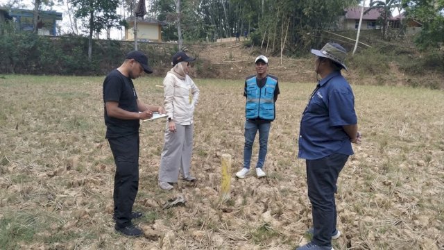 Petugas teknis (kiri) mencatat data hasil pengukuran lapangan sementara anggota tim lainnya berkoordinasi di lokasi survei yang berada di lahan terbuka di Kecamatan Sangalla, Kabupaten Tana Toraja. (Dok. Humas PLN UIP Sulawesi) 